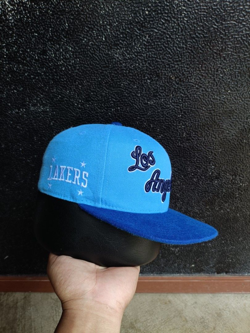 Mitchell & Ness Los Angeles Lakers Snapback Cap Blue (Category: Caps & Hats) located in Daet. Submitted by quickearth.ac7e7e (Listing ID 1470791479, Image 2). Description: - Brand: Mitchell & Ness - Style: Snapback hat with flat brim - Color: Bright blue with dark blue accents - Embroidery: 'Los Angeles' script on front, Lakers text and star graphics on the side - Closure: Adjustable blue plastic snapback - Condition: Clean structure with neat st