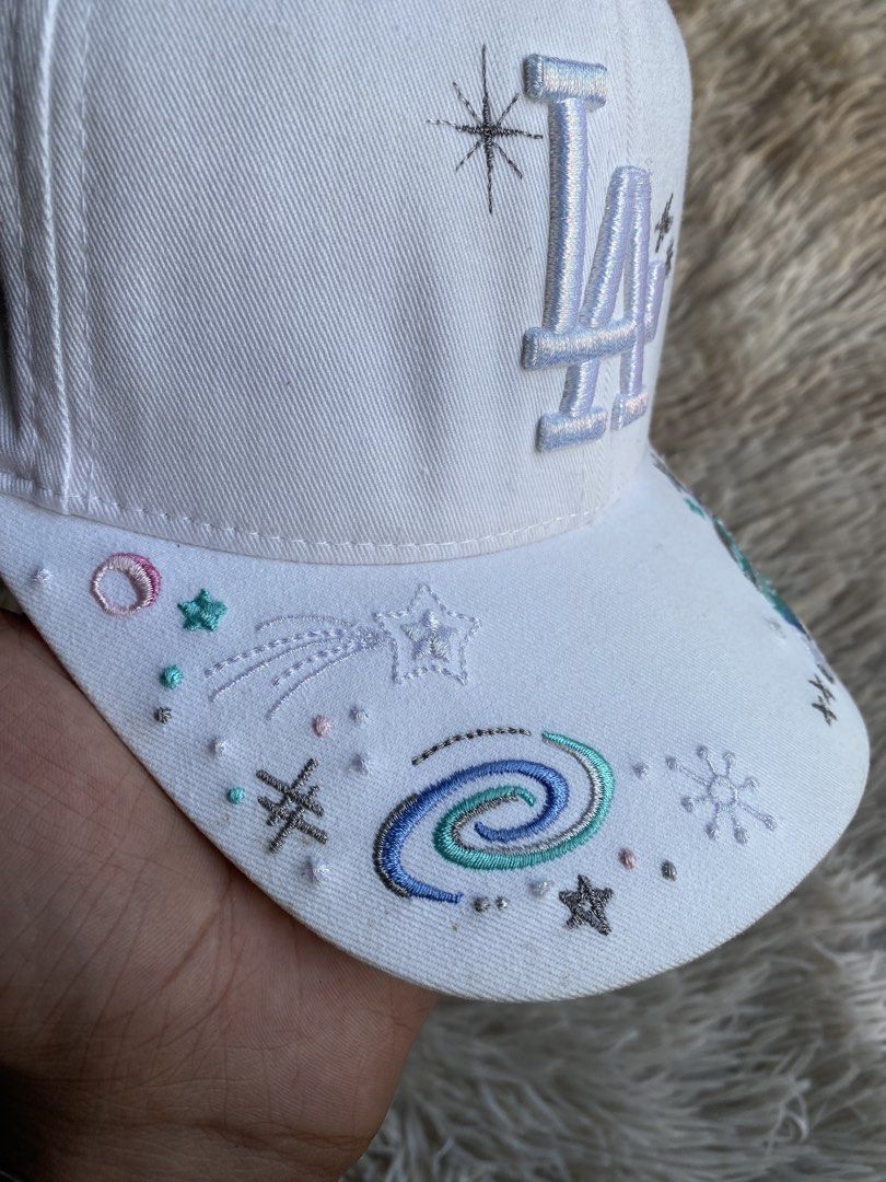 MLB LA Dodgers “Galaxy / Cosmic Custom Art” Cap (White) 🧢✨ (Category: Caps & Hats) located in Puerto Princesa. Submitted by thriftedheatshub (Listing ID 1470859788, Image 2). Description: 💰 Price: ₱679 + Shipping Fee🏷️ (Steal price) Condition: Good as New Condition (9.8/10 — pristine white crown & visor, heavy 3D embroidered “LA” logo with metallic silver thread accents, vibrant galaxy/planet/constellation embroidered custom art across brim) �