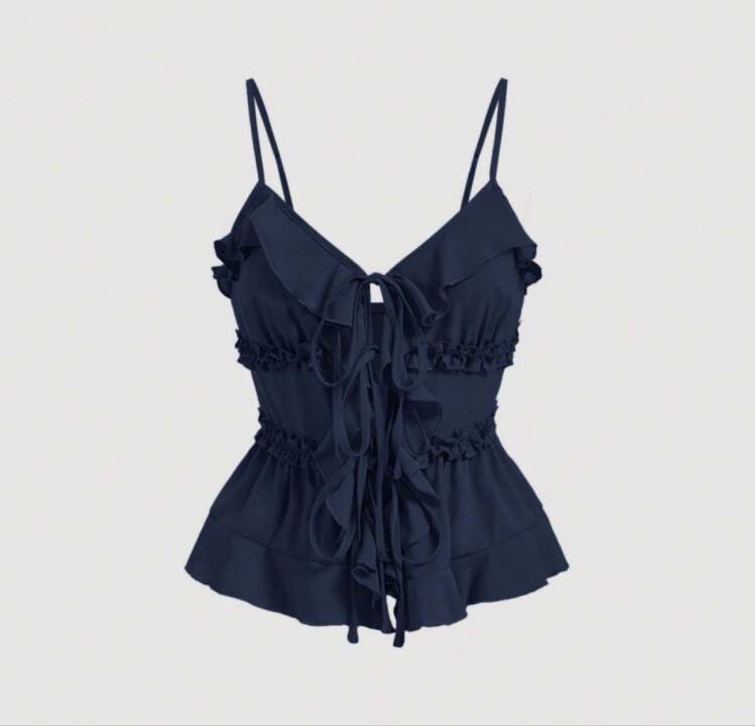 Navy Blue Ruffled Peplum Cami Top (Category: Sleeveless) located in Manila. Submitted by clothesofitiew (Listing ID 1470775507, Image 1). Description: - Color: Navy blue - Design: Cute ruffles along neckline, waist, and hem with multiple front tie strings - Style: Peplum flare with thin spaghetti straps and clean ruffled back tier - Versatile piece great for casual days or nights out.