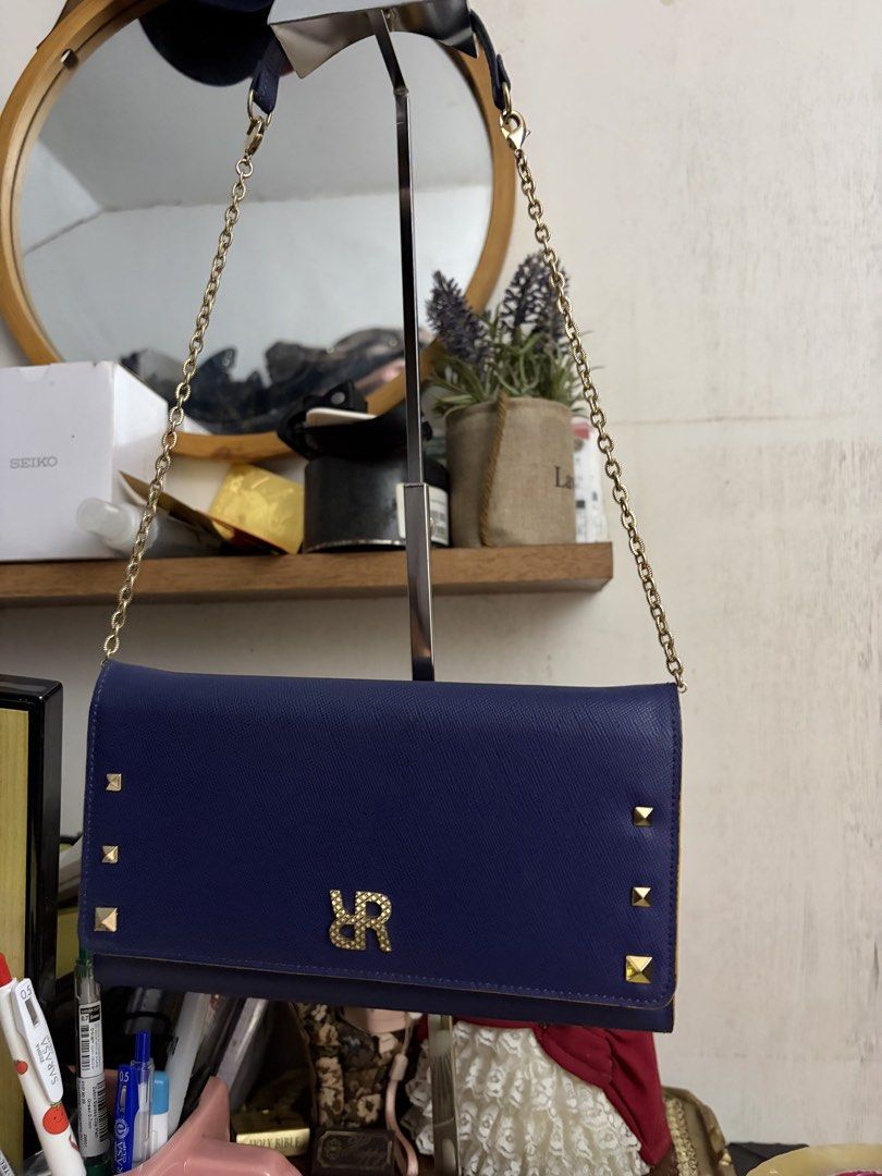 Navy Blue Wallet on Chain Crossbody Bag (Category: Cross-body Bags) located in Manila. Submitted by lynnalec25 (Listing ID 1470858896, Image 2). Description: Navy blue structured crossbody bag with gold tone hardware. Features gold pyramid studs along the bottom sides and an interlocking monogram logo clasp on the front flap. Detachable gold chain strap included. Interior opens to a bright yellow leather lining with multiple card slots, slip comp