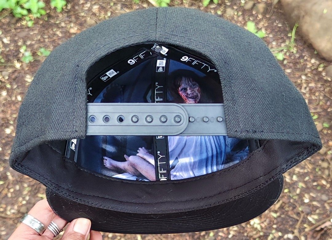 New Era The Exorcist 9Fifty Snapback Cap (Category: Caps & Hats) located in Manila. Submitted by sansmerci27 (Listing ID 1470903160, Image 3). Description: Black New Era 9FIFTY snapback cap featuring embroidered purple text of The Exorcist on the front and 'I'm Not Regan' on the side. Under-brim and interior lining feature a graphic print of Regan from the movie. Adjustable snapback closure at the back. Flat brim with original sticker still attac