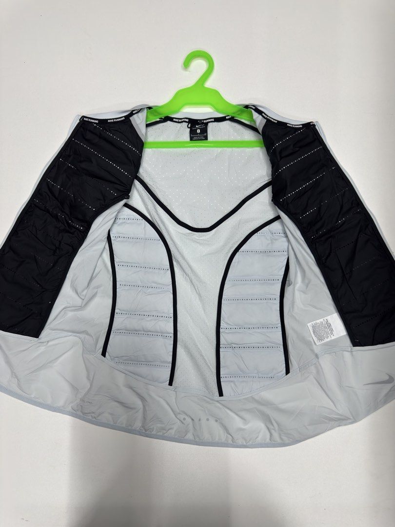 Nike Aeroloft Running Vest Size S (Category: Activewear) located in Bustos. Submitted by thenlnclot60500 (Listing ID 1470812265, Image 3). Description: - Brand: Nike Aeroloft - Item: Running Vest - Color: Light Grey and Black - Size: S - Material: 90% White Goose Down fill for lightweight warmth - Ventilation: Laser-perforated holes on upper back and chest for breathability - Design: Zip-up front with high collar - Safety: Reflective details for 