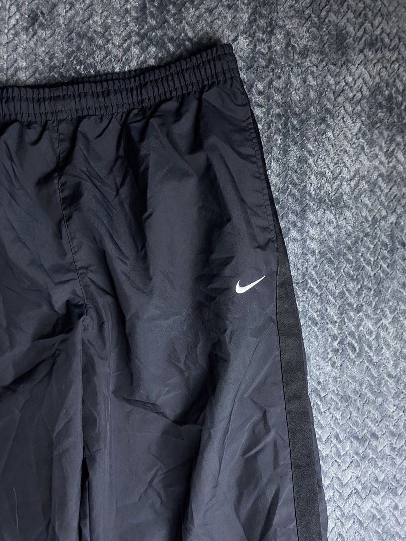 Nike Black Windbreaker Pants Size XL (Category: Joggers) located in Olongapo. Submitted by WAVYT (Listing ID 1470893621, Image 2). Description: - Brand: Nike - Item: Windbreaker Pants - Color: Black with white accents - Size: XL - Details: Embroidered white swoosh on left thigh, stylish side stripes down both legs - Comfort & Fit: Elastic waistband with adjustable white drawstring and breathable mesh lining - Storage: Functional back pocket with 