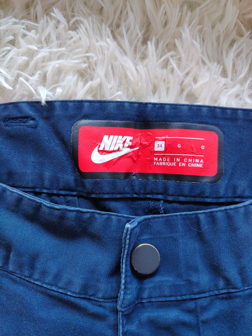 Nike Blue Cargo Pants Size 34 (Category: Joggers) located in Caba. Submitted by valerie_18947 (Listing ID 1470778844, Image 3). Description: - Brand/Model: Nike Cargo Pants - Size: 34 (Large fit) - Color/Wash: Dark blue - Material: 98% cotton, 2% elastane (Pocket bags: 65% polyester, 35% cotton) - Features: Zippered cargo pockets, button closure, zippered fly - Details: Red inner waistband label with Nike logo.