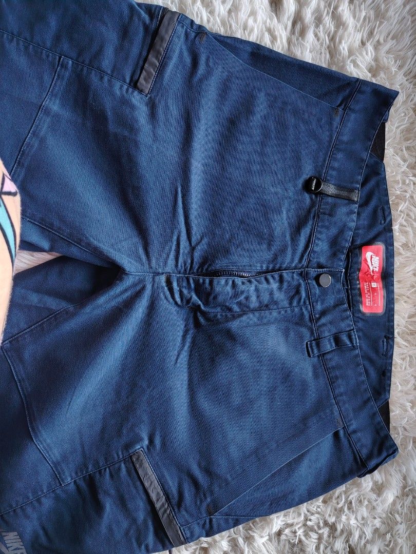 Nike Blue Cargo Pants Size 34 (Category: Joggers) located in Caba. Submitted by valerie_18947 (Listing ID 1470778844, Image 2). Description: - Brand/Model: Nike Cargo Pants - Size: 34 (Large fit) - Color/Wash: Dark blue - Material: 98% cotton, 2% elastane (Pocket bags: 65% polyester, 35% cotton) - Features: Zippered cargo pockets, button closure, zippered fly - Details: Red inner waistband label with Nike logo.