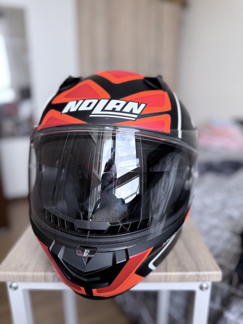 Nolan motorcycle helmet lexan polycarbonate size M (Category: Caps & Hats) located in Pasig City. Submitted by sherill888 (Listing ID 1470795012, Image 3). Description: - Brand/Model: Nolan Full Face Motorcycle Helmet - Design: Bold black, red, and white graphics - Visor: Clear visor currently installed - Condition: Impeccably clean inside and out - Inclusions: Original Nolan black fabric storage bag with Italian flag stripe design - Status: Road