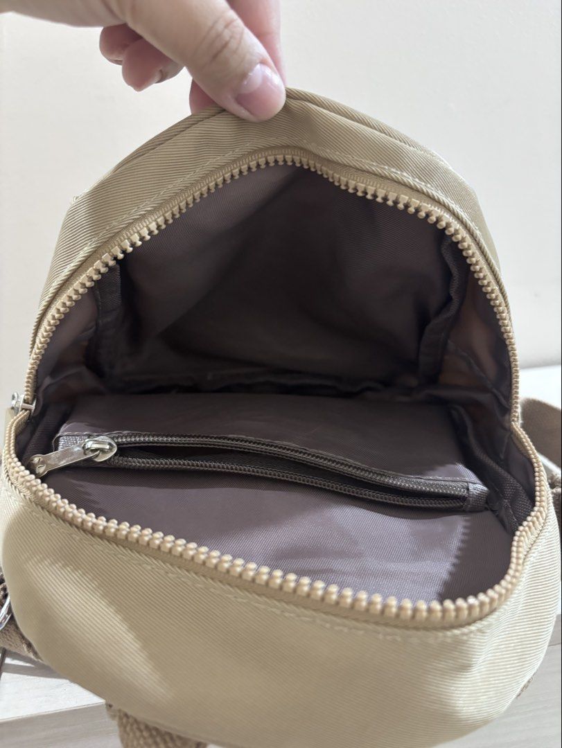 NuPrene Khaki Mini Backpack (Category: Backpacks) located in Caloocan City. Submitted by stuff_shop (Listing ID 1470835322, Image 3). Description: NuPrene mini backpack in khaki. Durable fabric with adjustable webbed shoulder straps and top grab handle. Main compartment zips open fully. Front flap pocket plus vertical side zipper pocket. Clean interior lining with an inner zippered pocket. Compact size for daily essentials, errands, or light trav