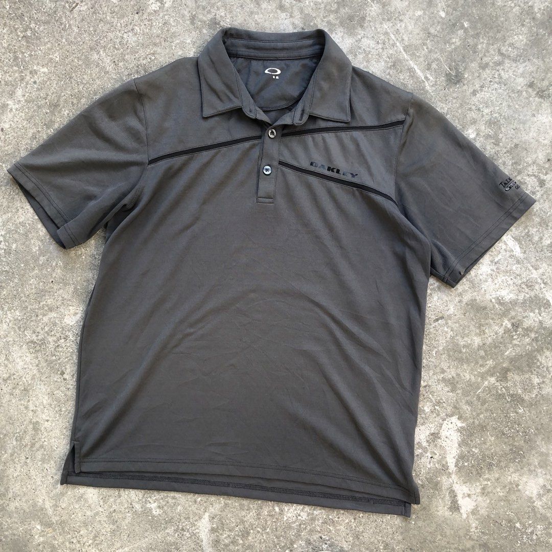 Oakley Golf Polo Shirt Grey (Category: Tshirts & Polo Shirts ) located in Manila. Submitted by threezzz (Listing ID 1470834868, Image 2). Description: - Brand: Oakley - Color: Grey with contrasting dark chest stripes - Material: Breathable textured fabric - Design: Short sleeves, standard collar, two-button placket with branded buttons - Branding: Oakley logo printed on left chest and back shoulder - Style: Casual sportswear / golf polo.