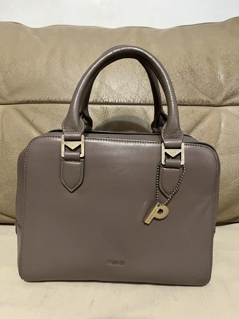 Picard Leather Satchel Handbag (Category: Luxury Bags & Wallets) located in Calamba. Submitted by jupreloved_ (Listing ID 1470792462, Image 3). Description: Picard taupe leather handbag with gold hardware. Features dual top handles, zip top closure, organized interior compartments, and a bonus back zip pocket. Brand: Picard Size: Medium Shipping through J&T. Payment are strictly through GCASH only, no COD. Exact size and color may be different fr