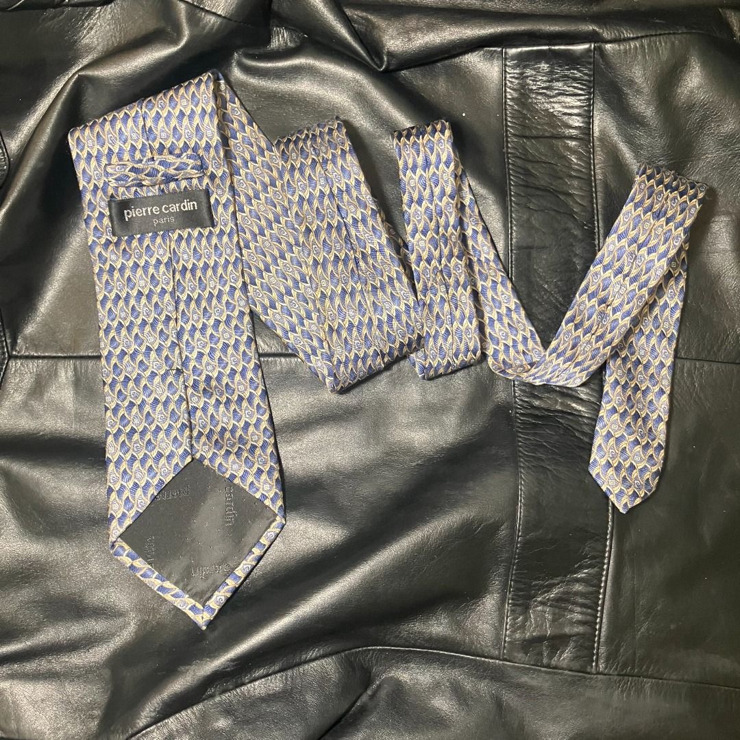 Pierre Cardin Paris 100% Silk Patterned Necktie (Category: Ties) located in Manila. Submitted by nellyfrustrado (Listing ID 1470808704, Image 3). Description: tem Specifics: Brand: Pierre Cardin Paris (Features branded logo label and keeper loop). Material: 100% Silk (Labeled "100% SILK / 100% SOIE / 100% SETA" and "HAND MADE"). Made in Italy. Colorway: Vibrant royal blue base intricately woven with gold, beige, and light blue geometric wave/scal