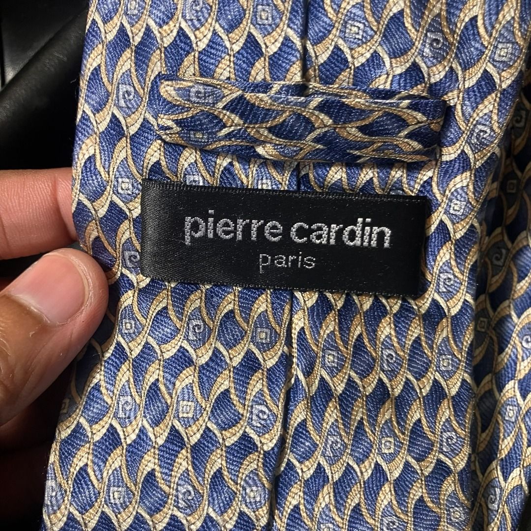 Pierre Cardin Paris 100% Silk Patterned Necktie (Category: Ties) located in Manila. Submitted by nellyfrustrado (Listing ID 1470808704, Image 2). Description: tem Specifics: Brand: Pierre Cardin Paris (Features branded logo label and keeper loop). Material: 100% Silk (Labeled "100% SILK / 100% SOIE / 100% SETA" and "HAND MADE"). Made in Italy. Colorway: Vibrant royal blue base intricately woven with gold, beige, and light blue geometric wave/scal