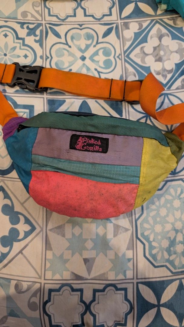 Pinked Gorilla Patchwork Fanny Pack Waist Bag (Category: Belt bags, Clutches and Pouches) located in Manila. Submitted by alypacis06 (Listing ID 1470764616, Image 2). Description: - Brand: Pinked Gorilla - Design: Multi-color patchwork in yellow, pink, blue, purple, and green - Strap: Adjustable orange strap with a sturdy black buckle - Pockets: Secure top zip closure, front pocket, and interior zippered compartments - Versatility: Can be worn cr