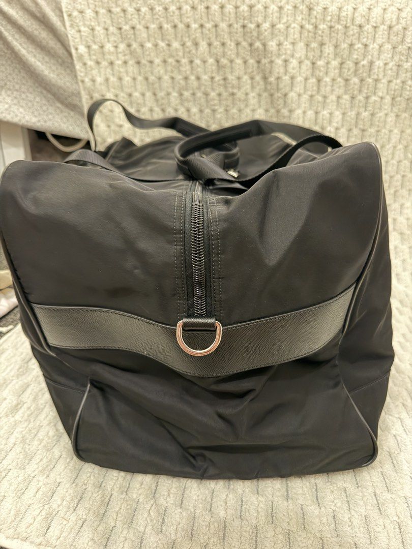 Prada Black Nylon Duffle Bag (Category: Luxury Bags & Wallets) located in Paranaque City. Submitted by juliasmomsy (Listing ID 1470795993, Image 3). Description: Black Prada duffle bag made from durable nylon. Classic triangle logo plaque on the front. Double top handles with sturdy zipper closure. Includes matching luggage tag and combination padlock. Interior lined with Prada signature jacquard fabric, featuring zippered pocket. Bottom protecte