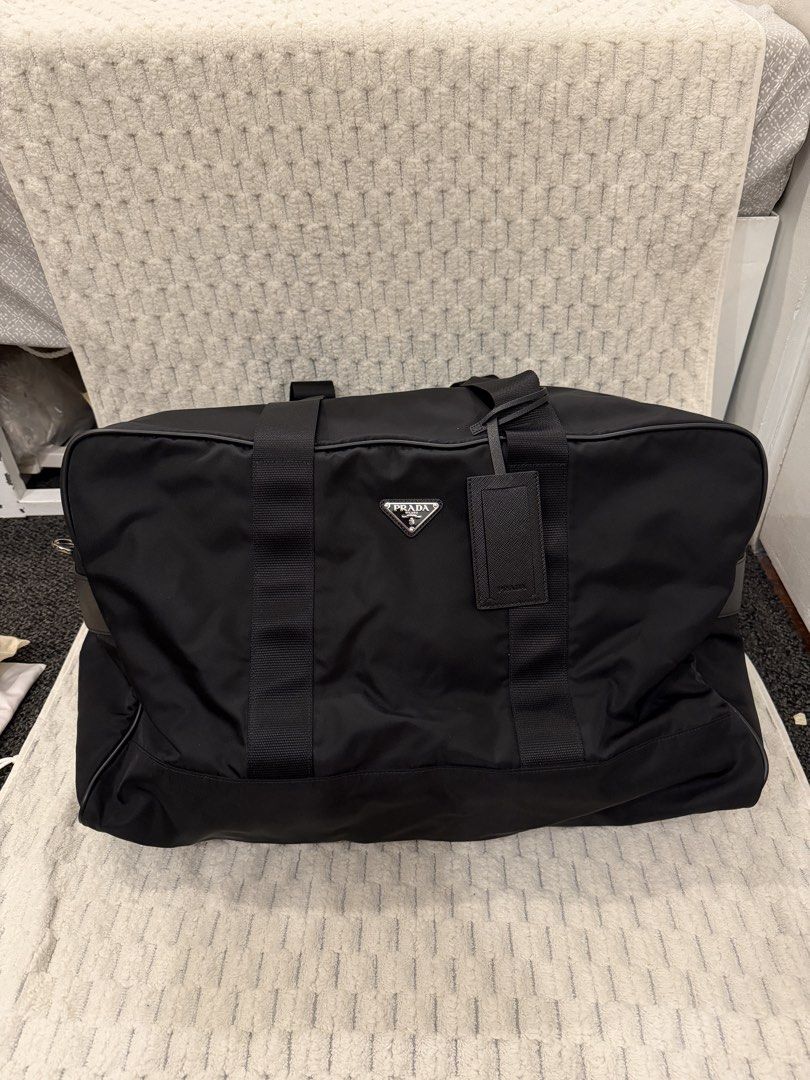 Prada Black Nylon Duffle Bag (Category: Luxury Bags & Wallets) located in Paranaque City. Submitted by juliasmomsy (Listing ID 1470795993, Image 1). Description: Black Prada duffle bag made from durable nylon. Classic triangle logo plaque on the front. Double top handles with sturdy zipper closure. Includes matching luggage tag and combination padlock. Interior lined with Prada signature jacquard fabric, featuring zippered pocket. Bottom protecte