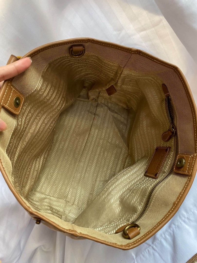 Prada Canvas Tote Bag Beige Brown (Category: Luxury Bags & Wallets) located in Manila. Submitted by zenbear_6b2d8a (Listing ID 1470755851, Image 3). Description: - Authentic Prada tote bag in versatile beige canvas with rich brown leather trim - Features the large embroidered Prada Milano logo on the front - Elegant gold-tone hardware including buckle straps and rings - Structured side profile with a secure snap button closure - Signature Prada f