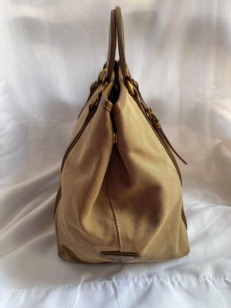 Prada Canvas Tote Bag Beige Brown (Category: Luxury Bags & Wallets) located in Manila. Submitted by zenbear_6b2d8a (Listing ID 1470755851, Image 2). Description: - Authentic Prada tote bag in versatile beige canvas with rich brown leather trim - Features the large embroidered Prada Milano logo on the front - Elegant gold-tone hardware including buckle straps and rings - Structured side profile with a secure snap button closure - Signature Prada f