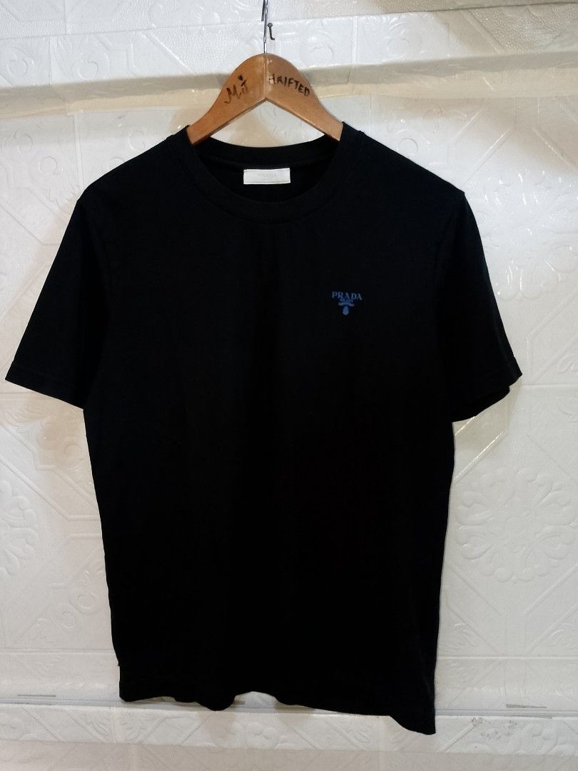 Prada Milano Black T-Shirt Size M (Category: Shirts) located in Manila. Submitted by mjthrifted_second (Listing ID 1470823934, Image 1). Description: - Brand: Prada Milano - Style: Crewneck short sleeve tee - Color: Solid black with blue embroidered chest logo - Size: Medium (Standard fit) -Dimes: 21/27 - Material: Premium cotton - Origin: Made in Italy - Authenticity: Interior neck label and wash tags intact (Style Code: UCS339) - Trusted Carous