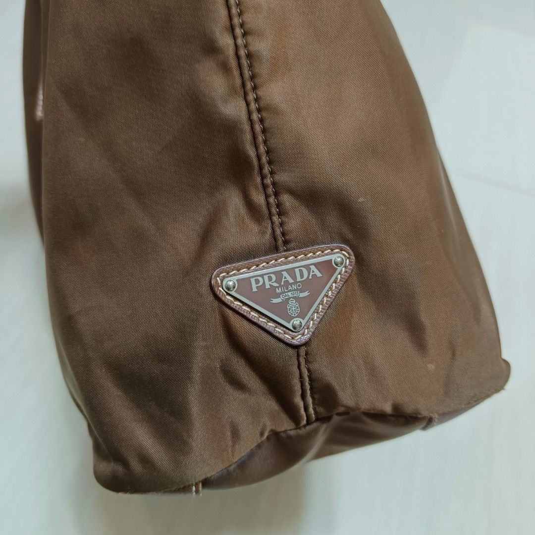 PRADA Nylon Tote Bag Shoulder Bag Brown (Category: Luxury Bags & Wallets) located in Nasugbu. Submitted by staffpicks1515 (Listing ID 1470827610, Image 3). Description: - Authentic brown Prada nylon tote and shoulder bag - Elegant leather handles and stylish buckled straps down the front - Iconic triangle logo plaque on top and debossed logo on the body - Secure riri zipper hardware and Prada metal plate inside - Deep brown textile lining with a 