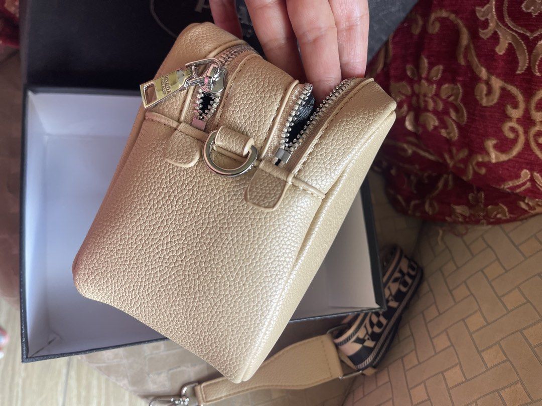 Prada Saffiano Leather Camera Bag Beige (Category: Luxury Bags & Wallets) located in Bulacan. Submitted by grazcloset (Listing ID 1470748493, Image 3). Description: - Brand: Prada - Color: Beige - Material: Textured leather with silver-tone hardware - Design: Boxy structure with dual zip compartments and matching front triangular logo plaque - Strap: Comfortable fabric logo strap included - Inclusion: Comes with original black Prada branded box -
