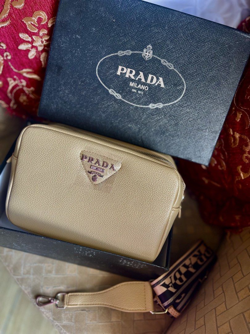 Prada Saffiano Leather Camera Bag Beige (Category: Luxury Bags & Wallets) located in Bulacan. Submitted by grazcloset (Listing ID 1470748493, Image 1). Description: - Brand: Prada - Color: Beige - Material: Textured leather with silver-tone hardware - Design: Boxy structure with dual zip compartments and matching front triangular logo plaque - Strap: Comfortable fabric logo strap included - Inclusion: Comes with original black Prada branded box -