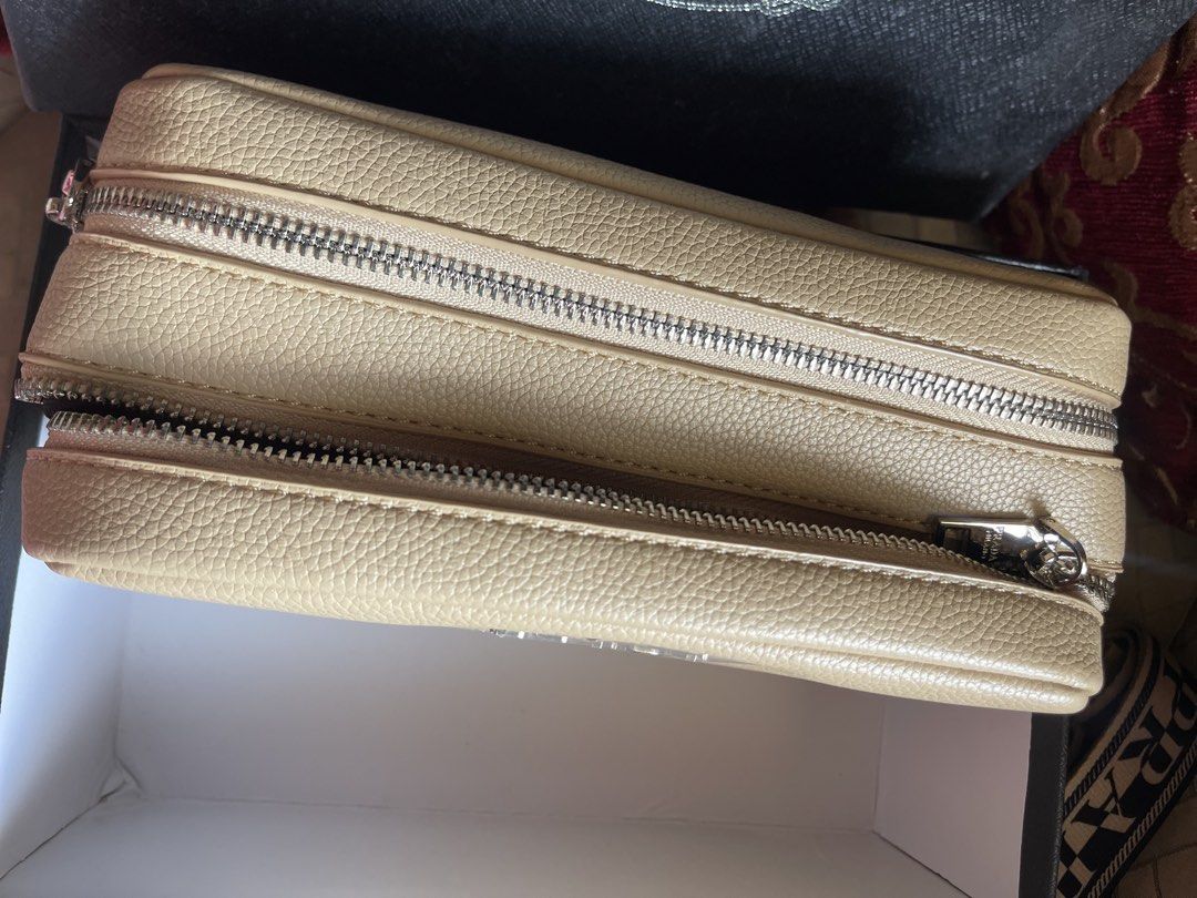 Prada Saffiano Leather Camera Bag Beige (Category: Luxury Bags & Wallets) located in Bulacan. Submitted by grazcloset (Listing ID 1470748493, Image 2). Description: - Brand: Prada - Color: Beige - Material: Textured leather with silver-tone hardware - Design: Boxy structure with dual zip compartments and matching front triangular logo plaque - Strap: Comfortable fabric logo strap included - Inclusion: Comes with original black Prada branded box -