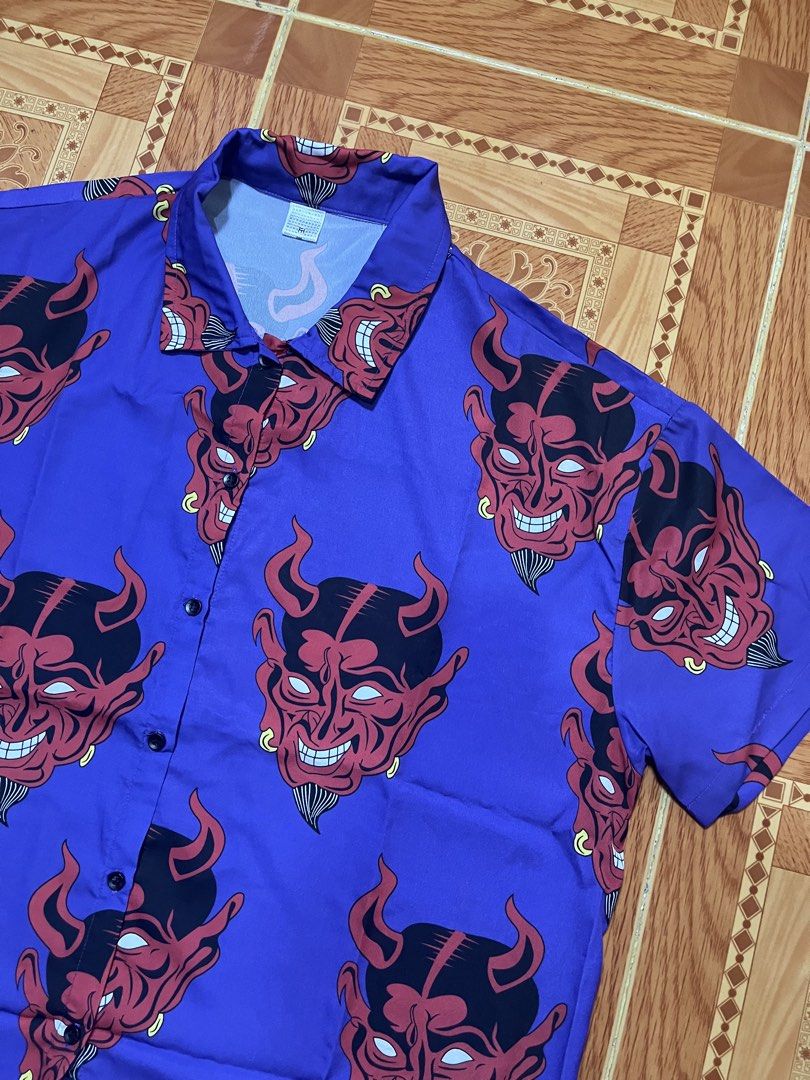 Purple Short Sleeve Button Up Devil Demon Face Print Shirt (Category: Tshirts & Polo Shirts ) located in Kidapawan. Submitted by azythrift (Listing ID 1470820524, Image 2). Description: - Color: Purple with bold red devil face graphic print - Style: Short sleeve button-up shirt, streetwear statement piece - Details: Standard collar, front button closure - Fabric: Lightweight and comfortable - Condition: Brand new / Excellent quality.