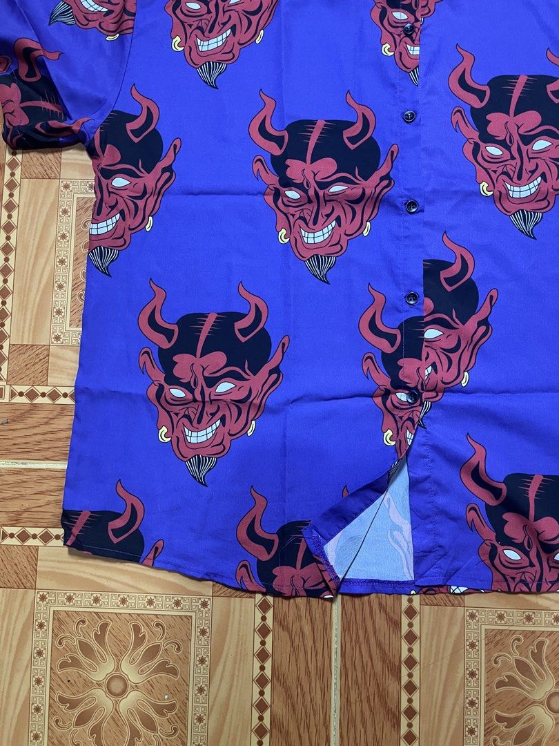 Purple Short Sleeve Button Up Devil Demon Face Print Shirt (Category: Tshirts & Polo Shirts ) located in Kidapawan. Submitted by azythrift (Listing ID 1470820524, Image 3). Description: - Color: Purple with bold red devil face graphic print - Style: Short sleeve button-up shirt, streetwear statement piece - Details: Standard collar, front button closure - Fabric: Lightweight and comfortable - Condition: Brand new / Excellent quality.