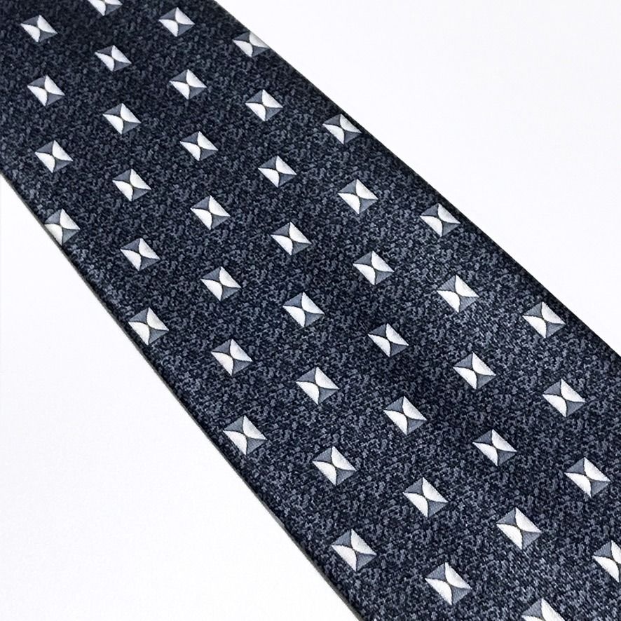 Rene Chagal Geometric Pattern Slate Blue Neck Tie (Category: Ties) located in Taguig. Submitted by retrogaze (Listing ID 1470851142, Image 3). Description: This necktie by Rene Chagal features a slate blue ground with a subtle, stippled micro-pattern. The body is decorated with an orderly geometric foulard pattern of small, square bowtie-like motifs rendered in crisp white, light grey, and charcoal accents. Recommended Suit & Shirt Pairings: • Th