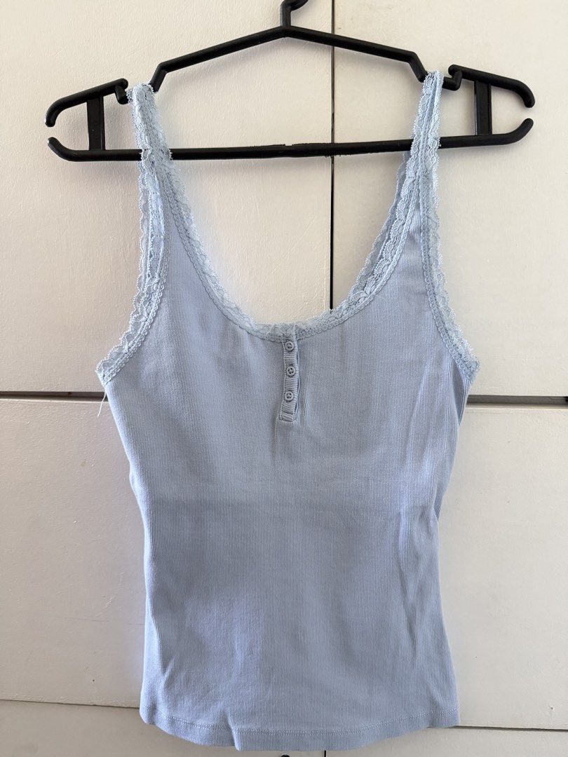 Ribbed lace trim cami tank top (Category: Sleeveless) located in Manila. Submitted by mnlclaudia (Listing ID 1470790381, Image 1). Description: - Color: Light blue - Material: Soft, stretchy cotton - Features: Delicate lace trim on scoop neckline and straps, functional front buttons - Fit: Body-hugging - Styling: Great for layering or wearing solo with jeans, skirts, or leggings.