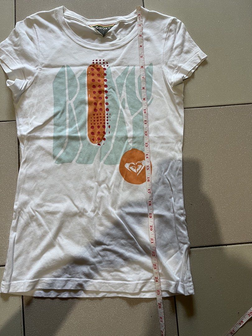 Roxy Graphic Print Short Sleeve T-Shirt (Category: Shirts) located in Siniloan. Submitted by marceiron316276 (Listing ID 1470848984, Image 3). Description: - Brand: Roxy - Color: White with turquoise and orange graphic print - Size: S - Material: Comfortable cotton feel - Design: Classic crew neck, short sleeves - Measurements: ~15.5" chest across, ~26.5" total length - Condition: Excellent.