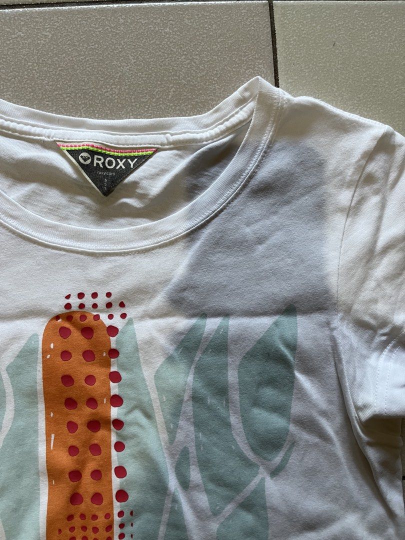Roxy Graphic Print Short Sleeve T-Shirt (Category: Shirts) located in Siniloan. Submitted by marceiron316276 (Listing ID 1470848984, Image 2). Description: - Brand: Roxy - Color: White with turquoise and orange graphic print - Size: S - Material: Comfortable cotton feel - Design: Classic crew neck, short sleeves - Measurements: ~15.5" chest across, ~26.5" total length - Condition: Excellent.