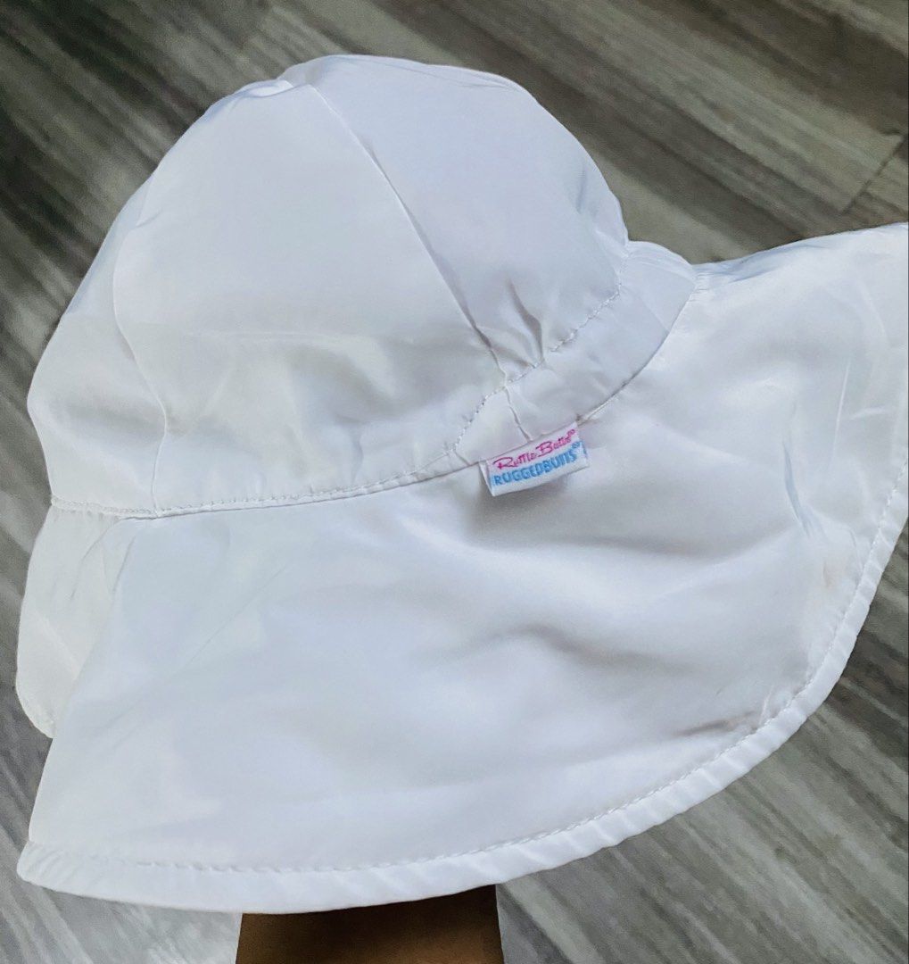 RuggedButts White Baby Sun Hat (Category: Babies & Kids Fashion) located in Caloocan City. Submitted by lovemyclothes21 (Listing ID 1470757533, Image 3). Description: - Brand: RuggedButts - Size: 0-6 Months - Color: Plain white (goes with any outfit) - Material: 100% polyester shell and lining with breathable mesh - Features: Wide brim for sun protection and a secure chin strap for windy days - Condition: Brand new / Excellent.