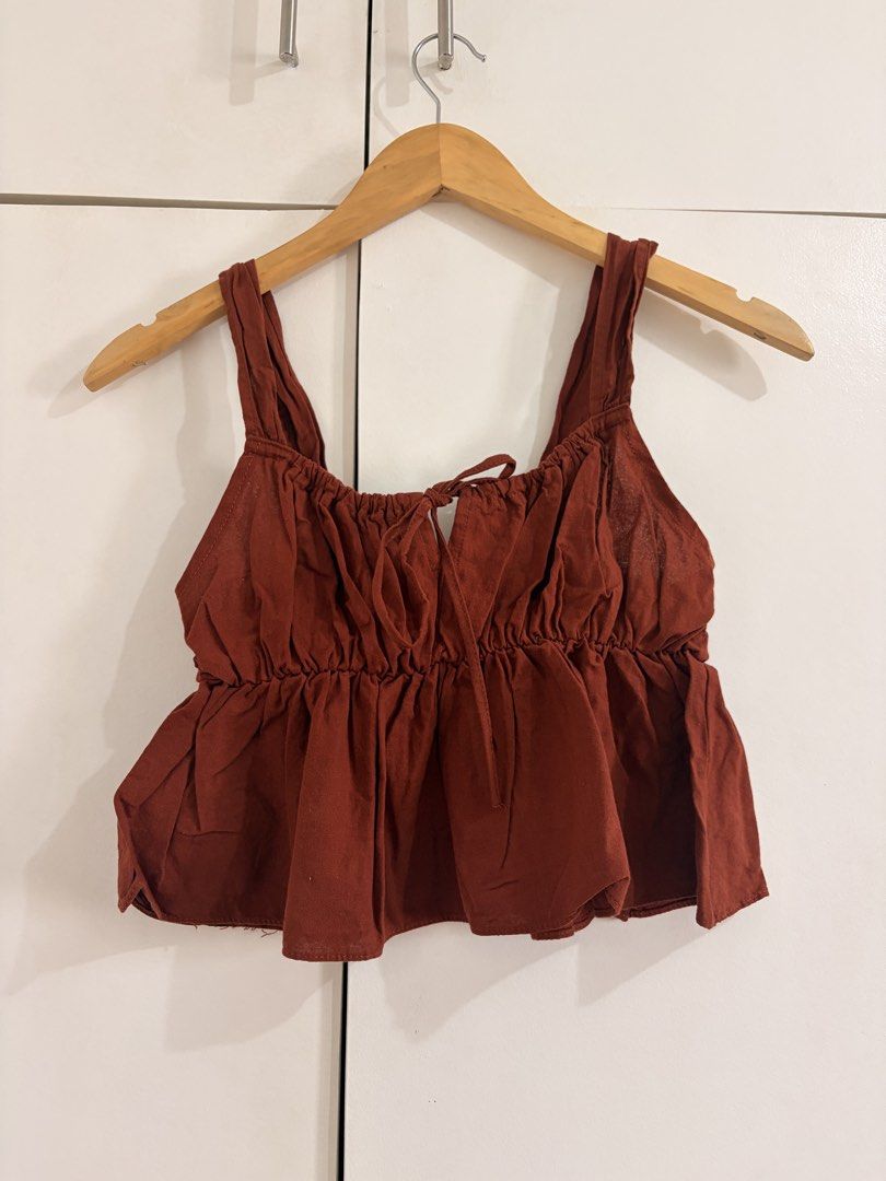 Rust red ruffled crop top with tie detail (Category: Sleeveless) located in Marikina City. Submitted by _bananahanaa (Listing ID 1470798919, Image 1). Description: - Color: Rust Red - Style: Crop top with flouncy peplum hem and gathered bodice - Details: Thick straps, front self-tie string, and elasticized back band for a secure fit - Fabric: Lightweight and breathable - Perfect for: Casual days out, best paired with high-waisted jeans - Conditio