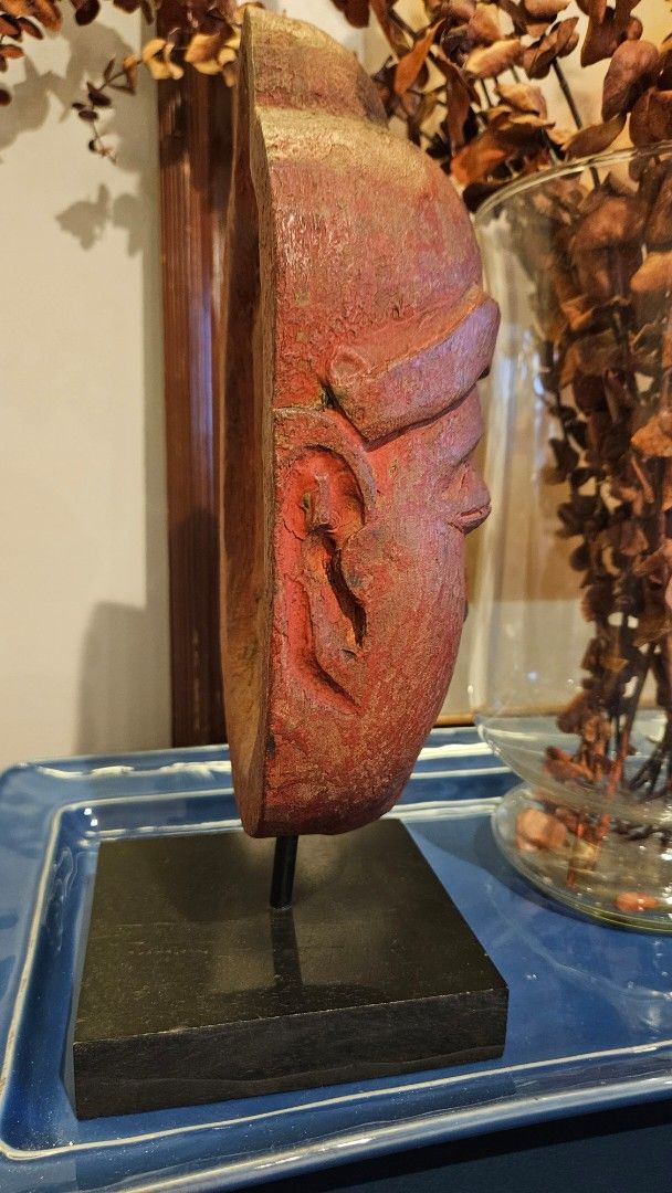Rustic Smiling Wood Buddha Head Sculpture on Stand (Category: Wall Decor) located in Manila. Submitted by cosmicshark-cd31f1 (Listing ID 1470878621, Image 3). Description: - Hand-carved wooden Buddha head sculpture - Mounted on a sturdy black square metal stand - Distressed red and brown finish with visible wood grain and aging texture - Hollow backing showing traditional carving technique - Perfect unique tabletop decor for bookshelves or entryw