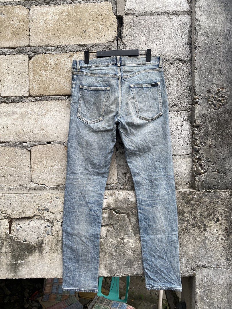 Saint Laurent Paris Wash Jeans (Category: Jeans) located in Candaba. Submitted by dejesus.bench17 (Listing ID 1470931578, Image 1). Description: - Brand: Saint Laurent Paris - Authentic Legit - Wash: Light wash with distressed vintage finish - Fit: Slim leg cut for everyday wear - Closure: Button fly with branded hardware and engraved zipper pull - Pockets: Classic five-pocket layout with back pocket tag detail - Issue cut wash tag - Condition: E