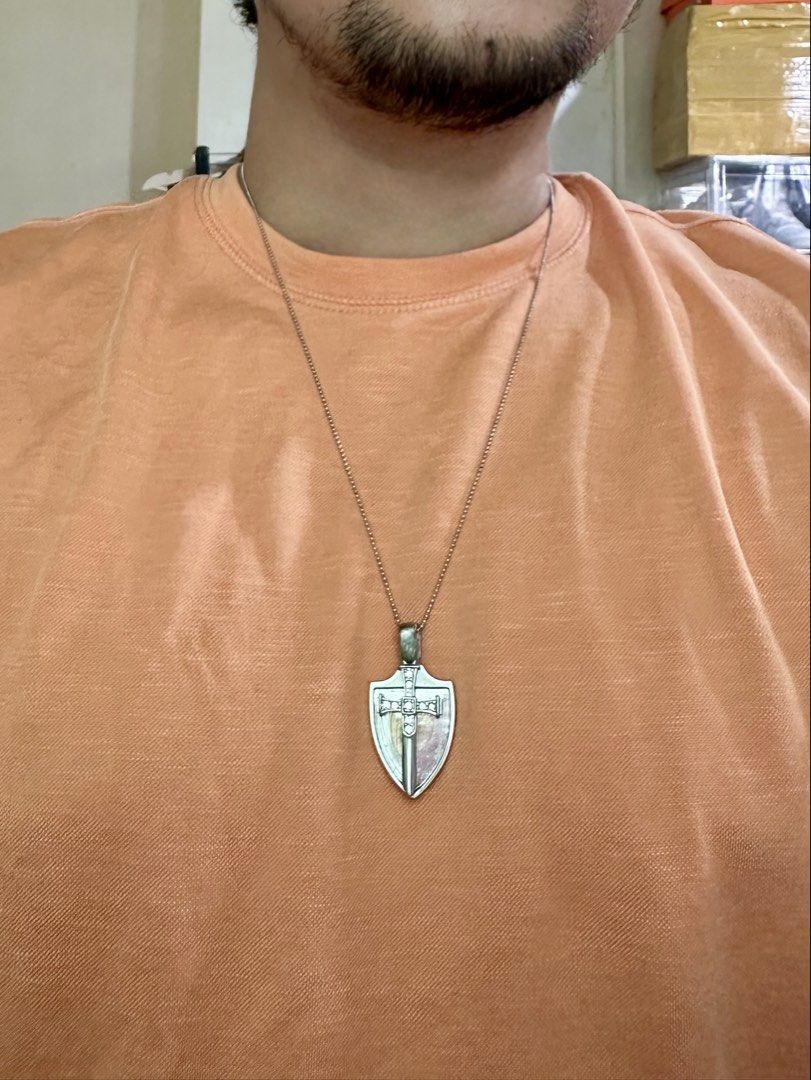 Saint Michael Sword and Shield Pendant Necklace (Category: Necklaces) located in Daet. Submitted by thrifthings2018 (Listing ID 1470751373, Image 2). Description: - Design: Silver-tone shield and sword with a rhinestone-embedded cross - Inclusion: Matching ball chain necklace with a secure clasp closure - Condition: Clean metal finish, ready to wear.