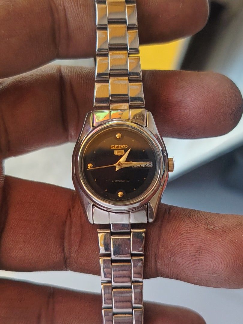 Seiko 5 Automatic Ladies Watch 𝚌𝚕𝚊𝚜𝚜𝚒𝚌 (Category: Women's Watches) located in Las Pinas. Submitted by mitchellestrada20202020 (Listing ID 1470785463, Image 2). Description: - Brand: Seiko 5 Automatic - Gender: Women's - Materials: Stainless steel link bracelet, silver-tone case - Dial: Dark dial with gold-tone hands and hour markers - Features: Day-date window at 3 o'clock position - Movement: Automatic wind-up mechanism - Condition: Excel