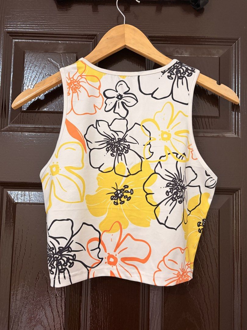SHEIN Floral Print Crop Top Size M (Category: Sleeveless) located in Marikina City. Submitted by _bananahanaa (Listing ID 1470802083, Image 2). Description: - Brand: SHEIN - Style: Sleeveless crop top with crew neckline - Design: White base with a vibrant yellow, orange, and black floral print - Size: M (EU 38, US 6) - Fabric: Lightweight and comfortable - Perfect for: Summer wear, easy to style with high-waisted shorts, skirts, or jeans fits sma