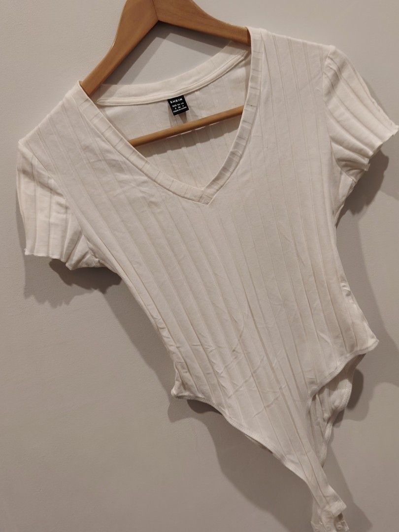 SHEIN White Ribbed V-Neck Bodysuit Size S (Category: Sleeveless) located in Manila. Submitted by jacelllamb12233 (Listing ID 1470859585, Image 2). Description: - Brand: SHEIN - Color: White with ribbed texture - Size: S (tag attached) - Design: Short sleeves, flattering V-neckline - Closure: Bottom snap buttons for easy wear - Material: Stretchy, comfortable fabric.