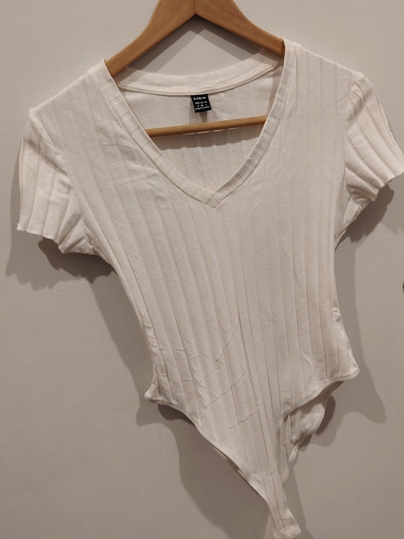 SHEIN White Ribbed V-Neck Bodysuit Size S (Category: Sleeveless) located in Manila. Submitted by jacelllamb12233 (Listing ID 1470859585, Image 3). Description: - Brand: SHEIN - Color: White with ribbed texture - Size: S (tag attached) - Design: Short sleeves, flattering V-neckline - Closure: Bottom snap buttons for easy wear - Material: Stretchy, comfortable fabric.