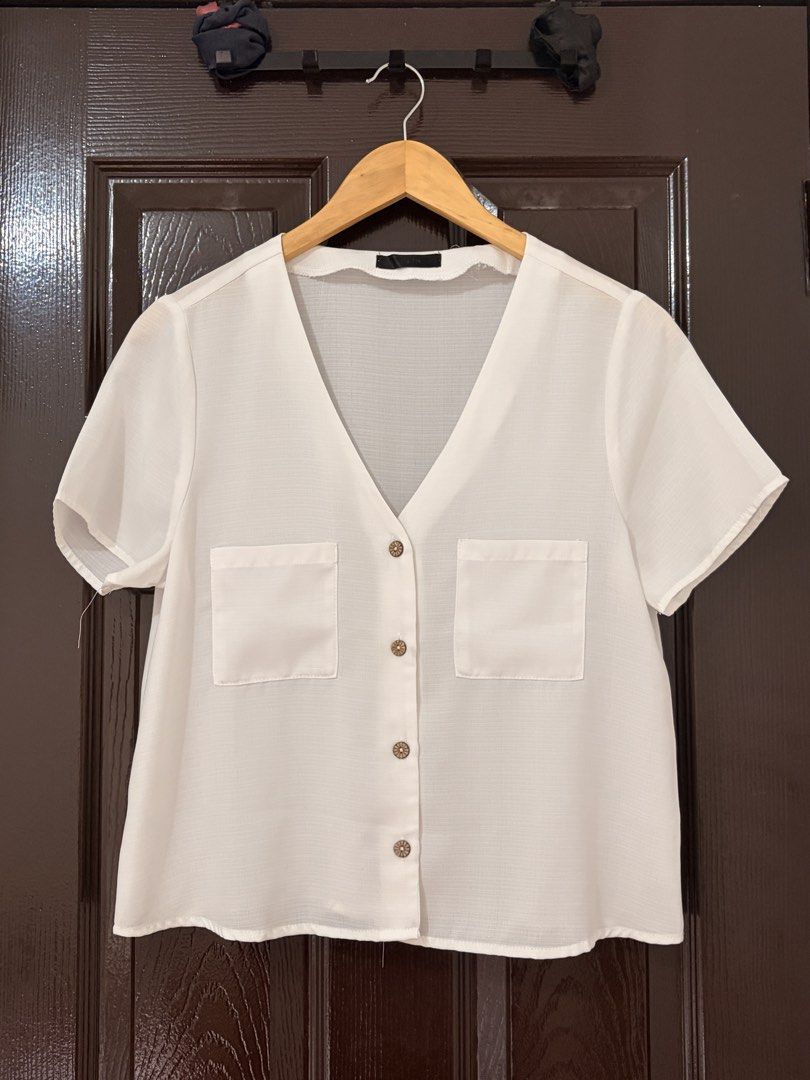 SHEIN White V-Neck Short Sleeve Button-Down Blouse (Category: Blouses) located in Marikina City. Submitted by _bananahanaa (Listing ID 1470802734, Image 1). Description: - Brand: SHEIN - Color: White - Style: V-neck button-down blouse with short sleeves - Details: Two chest pockets, stylish wooden-look front buttons - Material: Lightweight and breathable fabric - Condition: Clean, excellent, and ready to wear - Versatility: Perfect daily basic, e