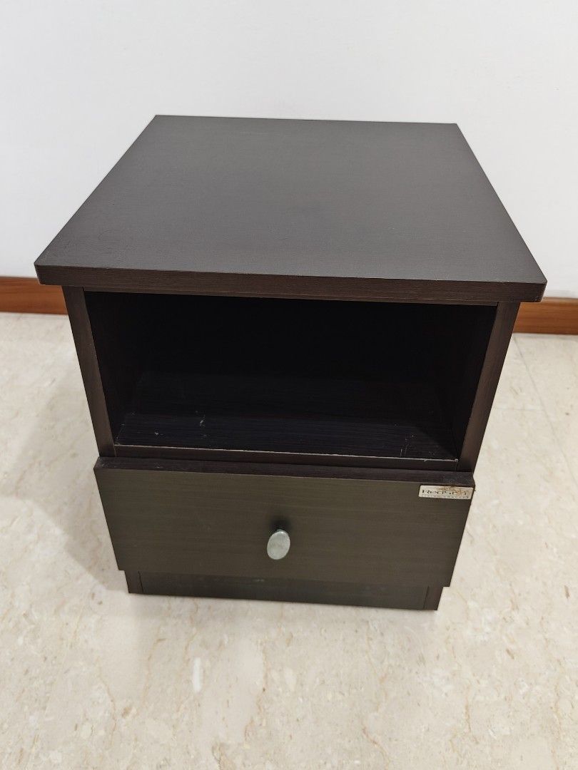 Side Table (Category: Tables & Sets) located in Singapore. Submitted by blindmaster (Listing ID 1470801978, Image 3). Description: - Type: Dark wood bedside table - Storage: Open top with 1 sliding pull-out drawer - Design: Solid dark brown finish with visible wood grain and silver-toned oval knob (discoloration) - Size: Compact, ideal for bedrooms or study rooms - Dimensions, L: 34cm x W: 38cm x H: 41.5cm - Item small enough to fit into the car 