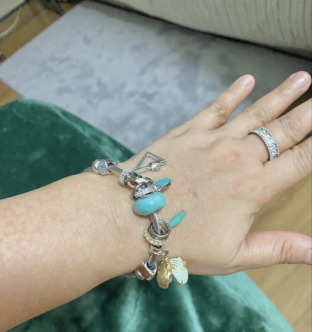 Silver Charm Bracelet with Turquoise and Shell Charms (Category: Bracelets) located in Makati City. Submitted by dpjanssen (Listing ID 1470867957, Image 3). Description: - Silver-tone cable bangle bracelet loaded with unique charms - Features a large turquoise bead, pearl ring spacer, geometric shape, teardrop stone, and gold-rimmed white shell dangle - Fits most wrist sizes comfortably - Metal shows minor wear near the ends.