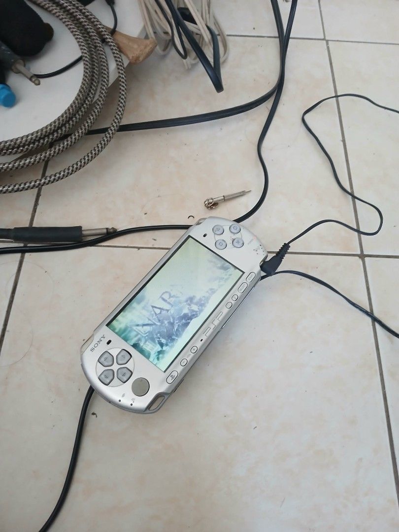 Sony PSP Silver Handheld Console with Games and Charger (Category: PlayStation) located in Cavite. Submitted by ambon2022 (Listing ID 1470930280, Image 2). Description: - Authentic Silver Sony PlayStation Portable (PSP) console bundle - Includes power adapter, carrying case, and a collection of UMD game discs - Fully tested: screen turns on and reads media successfully - Shows normal cosmetic wear and tear from regular use - Ideal retro gaming bu