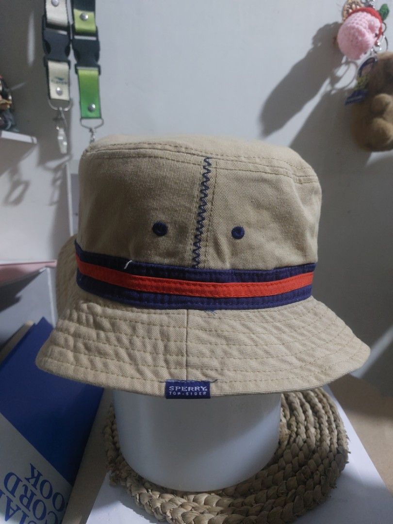 Sperry Top-Sider Beige Bucket Hat (Category: Caps & Hats) located in Magarao. Submitted by hotdogsandwich.flower (Listing ID 1470749992, Image 1). Description: - Brand: Sperry Top-Sider - Color: Tan with blue & orange stripe, contrast purple lining - Material: 100% breathable cotton - Fit: Standard fit - Details: Small logo tag on the side - Condition: Great for sunny days and outdoor wear - Origin: Made in China.
