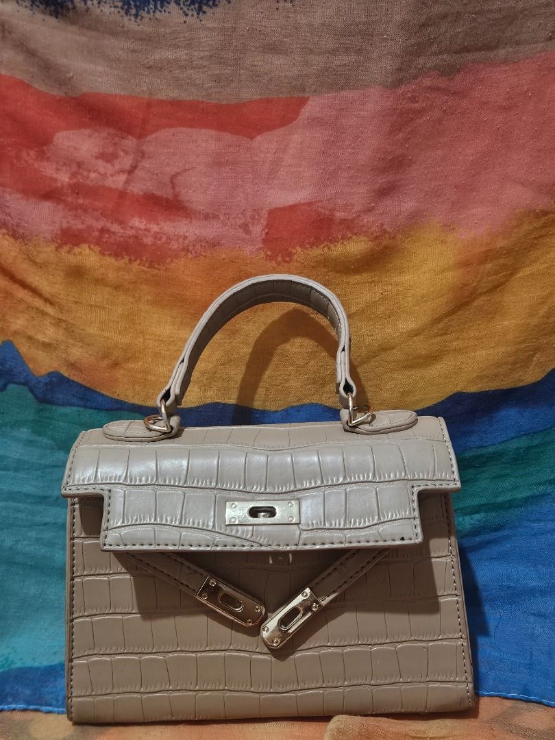 Taupe Crocodile Pattern Top Handle Handbag (Category: Luxury Bags & Wallets) located in Caloocan City. Submitted by gracevaultin.19 (Listing ID 1470876986, Image 2). Description: - Color: Versatile taupe neutral tone - Design: Structured trapezoid shape with a stylish single top handle - Texture: Elegant embossed crocodile pattern with a clean exterior finish - Closure: Front flap with a chic metal lock accent - Condition: Clean and well-maintain