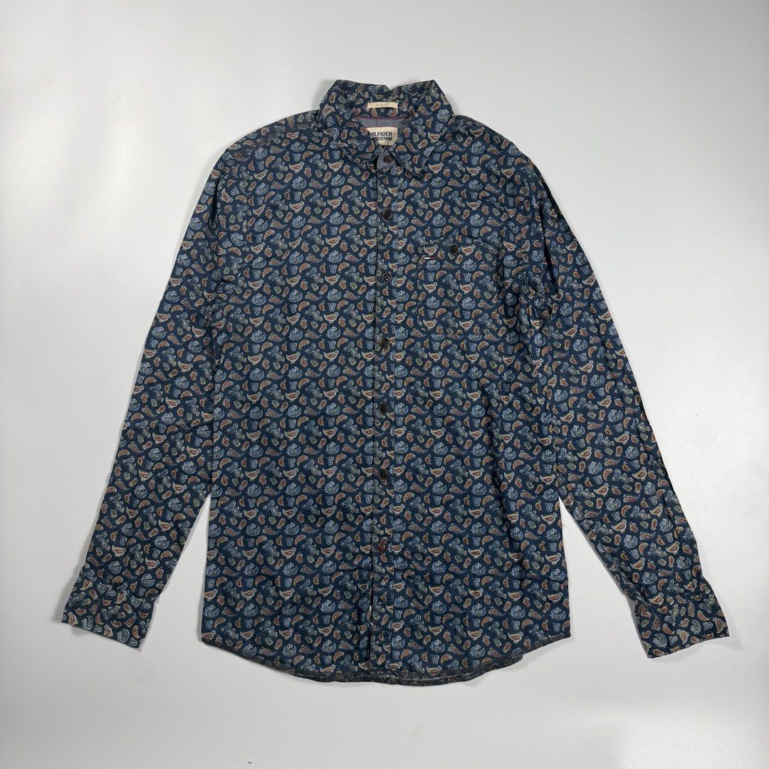 Tommy Hilfiger Denim Paisley (Category: Formal Shirts) located in Bacolod City. Submitted by freshstuff13 (Listing ID 1470928118, Image 1). Description: - Brand: Hilfiger Denim - Size: Small (Slim Fit) - Color/Pattern: Dark blue base with a multi-color all-over paisley design - Features: Button-down front with dark buttons, single chest pocket with a tiny flag logo tag, and a curved hemline - Condition: Excellent pre-loved condition - Perfect for