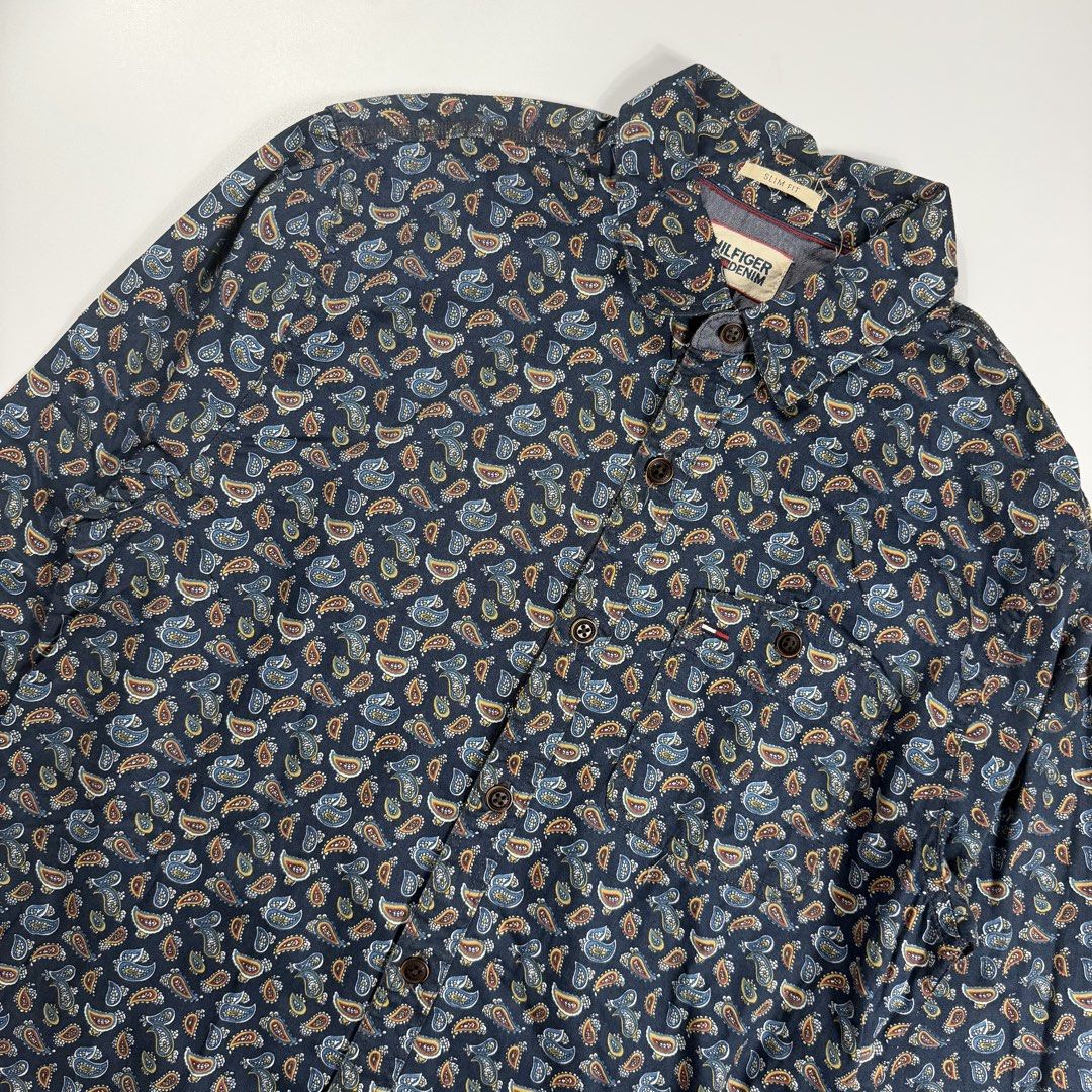 Tommy Hilfiger Denim Paisley (Category: Formal Shirts) located in Bacolod City. Submitted by freshstuff13 (Listing ID 1470928118, Image 2). Description: - Brand: Hilfiger Denim - Size: Small (Slim Fit) - Color/Pattern: Dark blue base with a multi-color all-over paisley design - Features: Button-down front with dark buttons, single chest pocket with a tiny flag logo tag, and a curved hemline - Condition: Excellent pre-loved condition - Perfect for