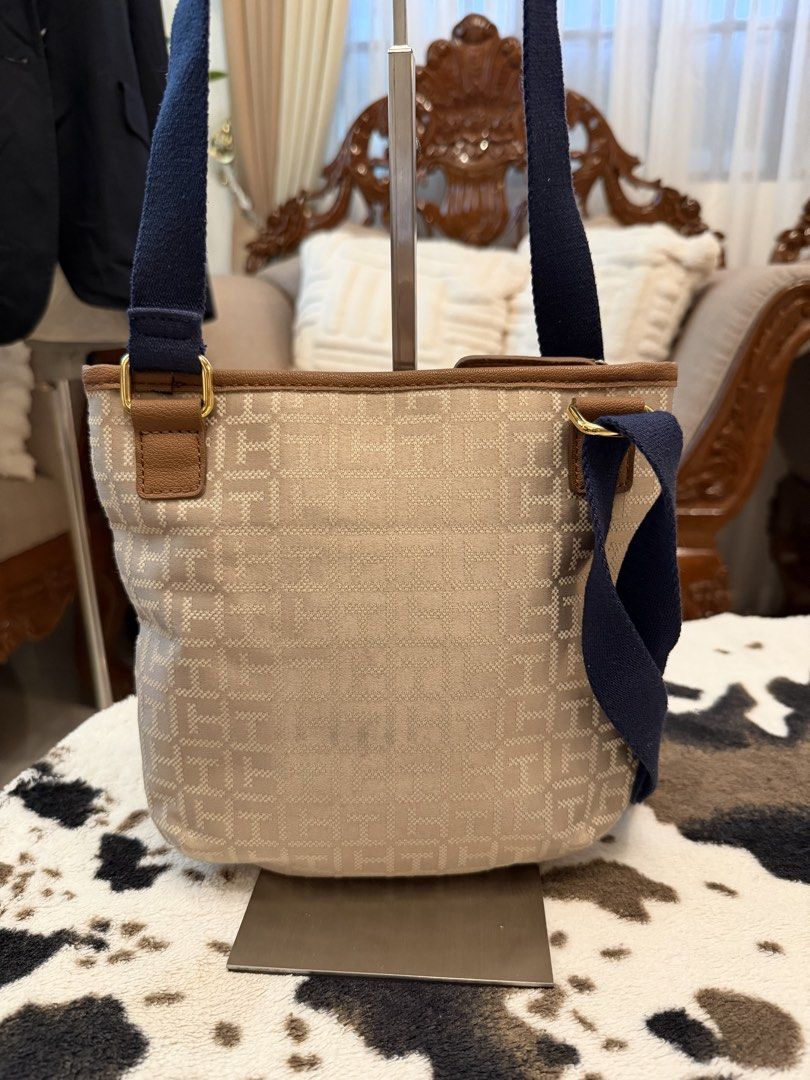 Tommy Hilfiger Monogram Canvas Shoulder Bag Navy Green (Category: Shoulder Bags) located in Santiago. Submitted by yrellagnoihsaf (Listing ID 1470764587, Image 2). Description: - Brand: Tommy Hilfiger - Material: Beige monogram canvas with dark navy straps - Design: Blue and green central stripe with decorative brown faux leather strap and gold-tone logo charm - Closure: Zip top - Interior: Dark navy lining with a red zipper pocket and Tommy Hilf