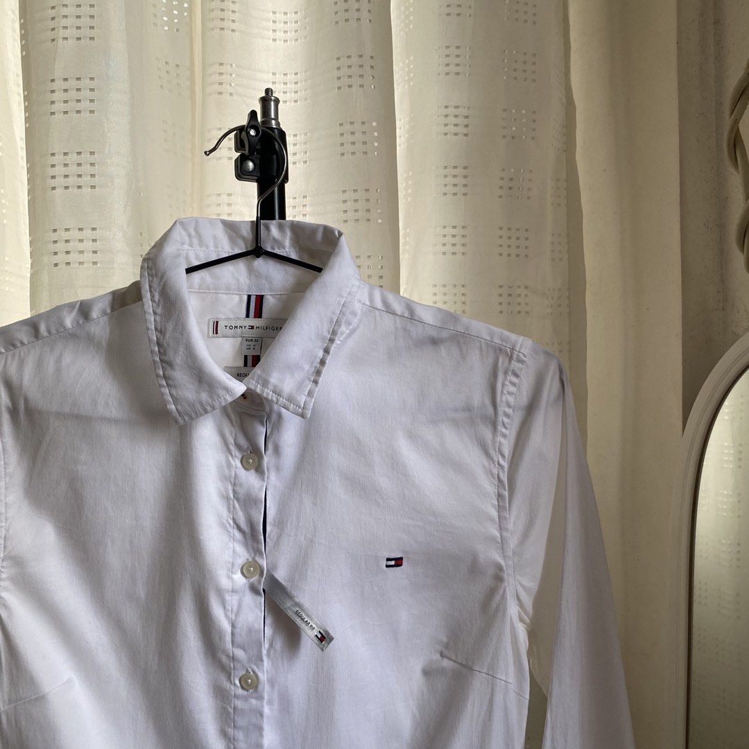 Tommy Hilfiger White Regular Fit Button Down Shirt (Category: Others Tops) located in Davao. Submitted by y2c0re (Listing ID 1470759412, Image 2). Description: Tommy Hilfiger Tagged EUR 32 Size 4/Large to medium - 19 width - 26 length Good as new condition No flaws 9.8/10 - Brand: Tommy Hilfiger - Color: Solid White - Condition: Brand new with tags attached - Fit: Regular fit - Material: Crisp cotton - Features: Long sleeves with button cuffs, cl